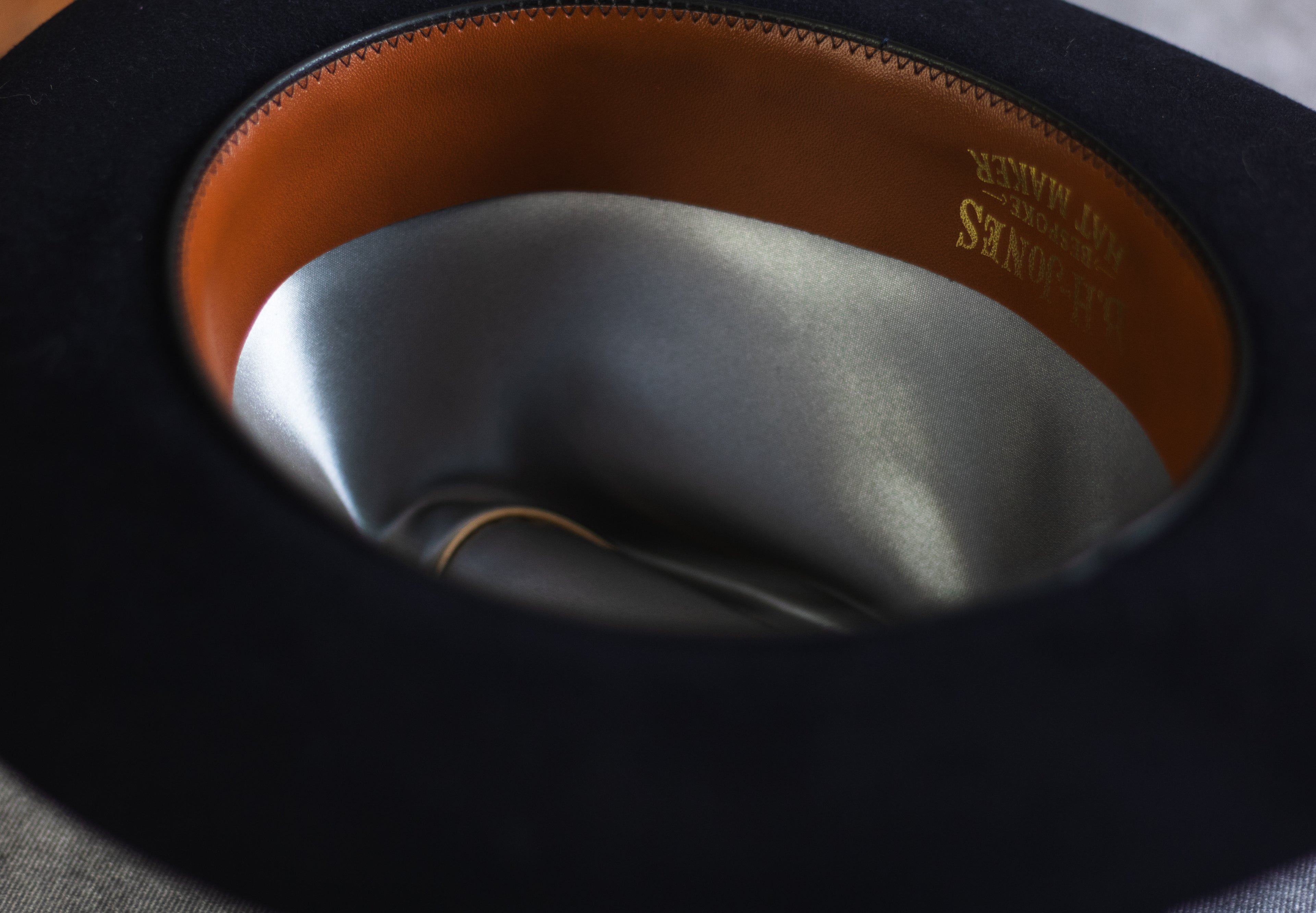 Close-up of a black hat with brown interior and visible brand name.